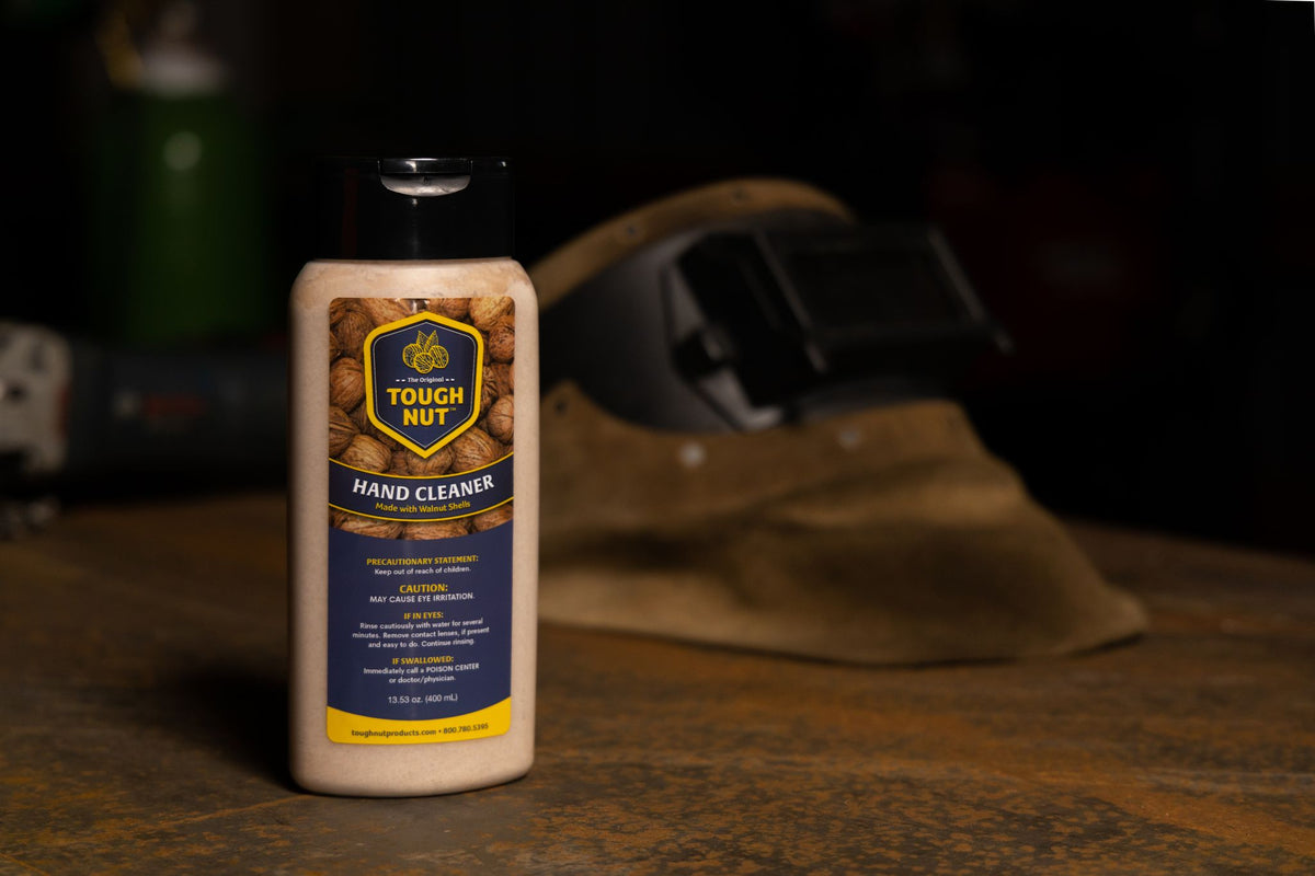 Tough Nut heavy duty hand cleaner 13.53 oz (400 mL) bottle on a workbench next to a leather welding glove
