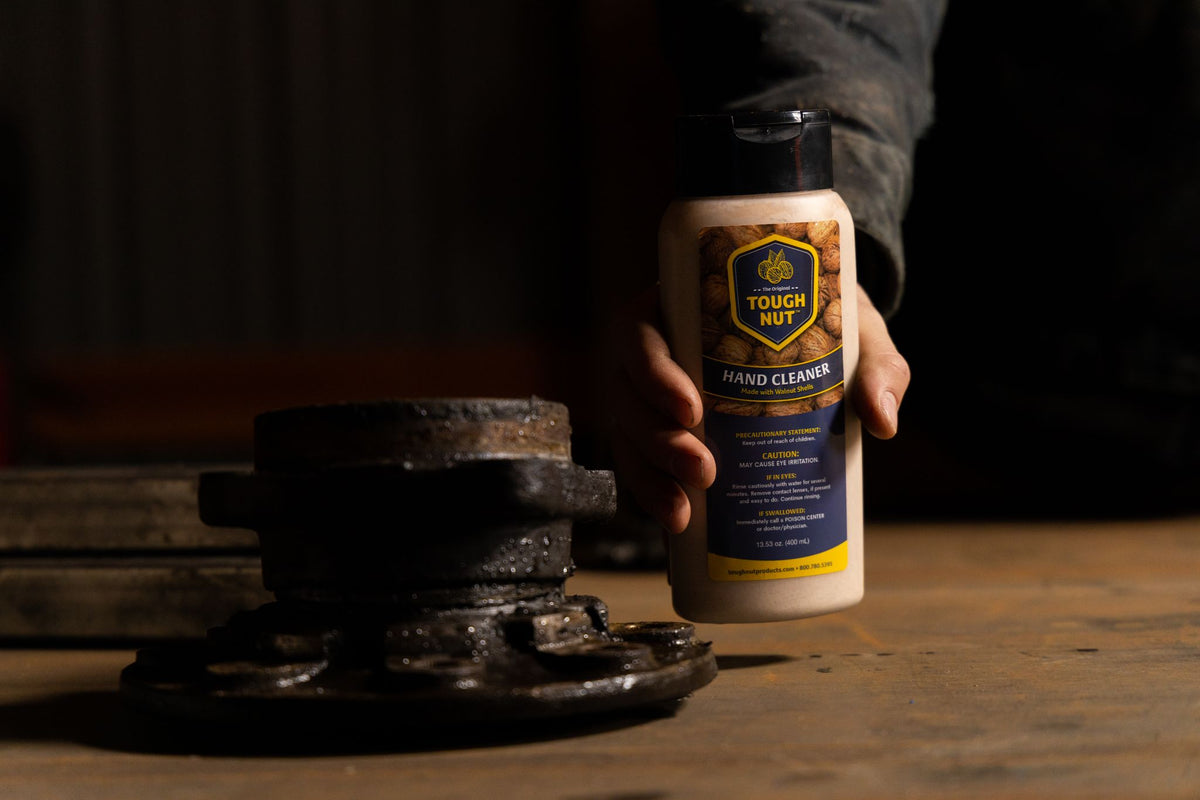 Hand setting a Tough Nut hand cleaner bottle down beside a greasy wheel hub