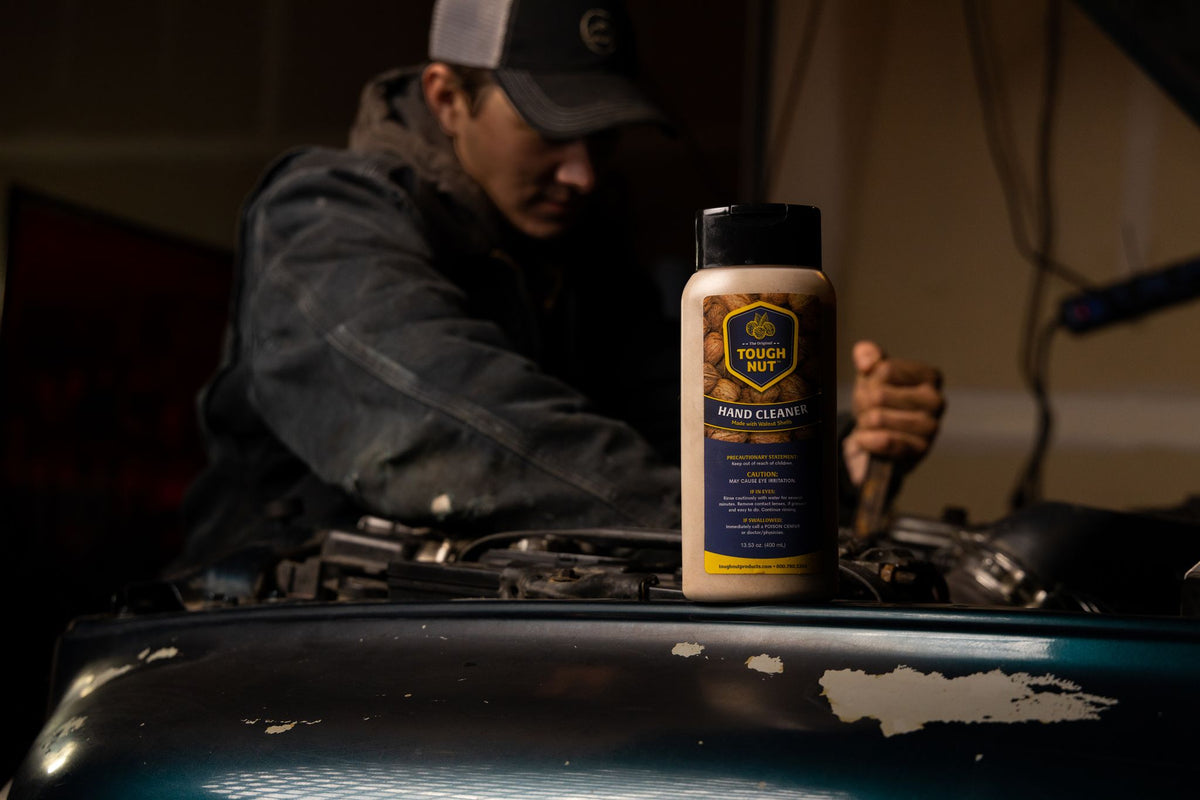 Tough Nut hand cleaner bottle on a truck hood while a mechanic works on the engine