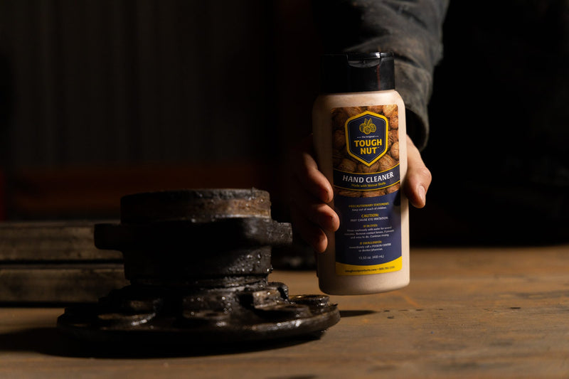 Hand setting a Tough Nut hand cleaner bottle down beside a greasy wheel hub